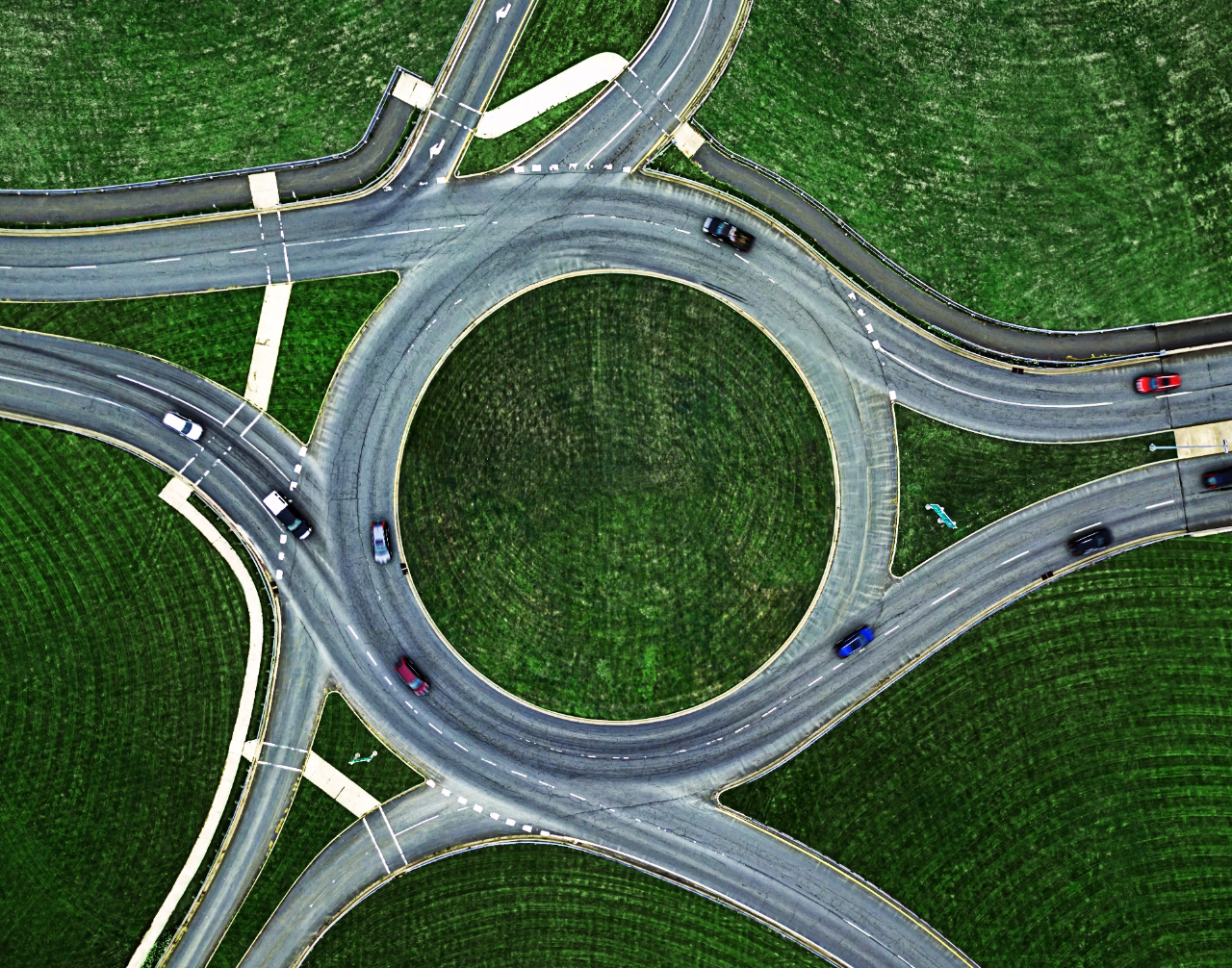 Vista aérea de un intercambiador de autopistas con vehículos entrando y saliendo de las rampas.